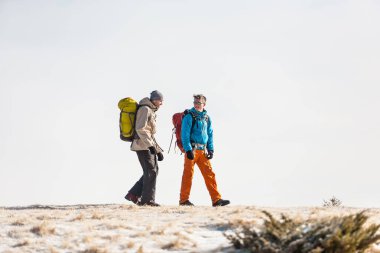 İki adam bir kış yürüyüş. Arkadaşlar doğal noktalar sırt çantaları ile seyahat. Dağcılar tırmanmaya. Yolcuları gökyüzüne karşı. Dağlarda hiking.