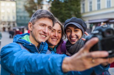 Arkadaşlar bir selfie al. Üç arkadaş güzel eski kasabanın içinden yürüyorlar. Avrupa şehirlere seyahat. İki kadın ve bir adam eski binalar fonunda fotoğraflandı.