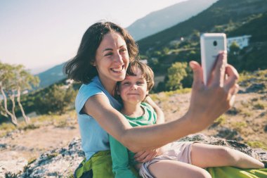 Bir kadın bir dağın tepesinde bir çocukla.