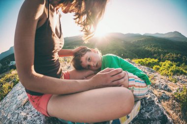 Yorgun çocuk annesinin ayakları üzerinde yatıyor.
