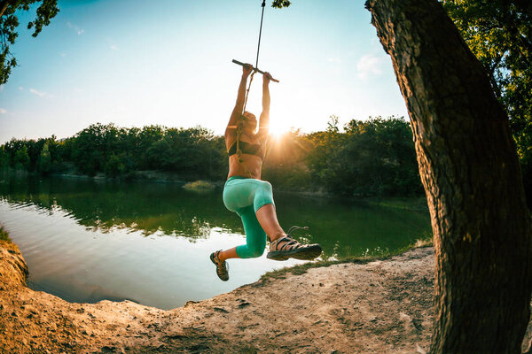 Прыгай в воду. Женщина отдыхает на озере. Качели из веревки и палки. Активный отдых на природе. Летнее веселье. Женщина качается на качелях. Объектив Fisheye
.