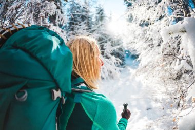 Sırt çantası kış dağlarda olan kadın. Doğal yerlere seyahat. Trekking sopa bir sarışınla portresi. Bir turist karlı bir orman yoluyla yürür. Etkin boş ve yaşam tarzı. Gülümseyen kız.