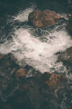 Dağ dere ve büyük taşlar. Ormandaki fırtınalı creek yakın çekim. Nehir kıyısında büyük ıslak taşlar. Küçük şelale.