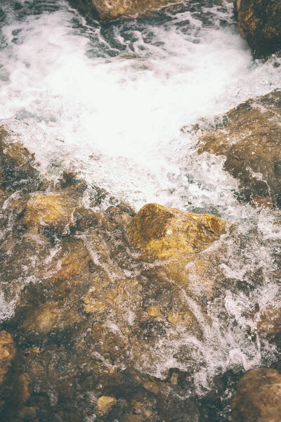 Mountain stream and large stones. Stormy creek in the forest close up. Large wet stones on the banks of the river. Little waterfall.