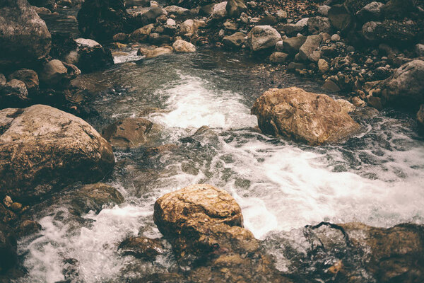 Mountain stream and large stones. Stormy creek in the forest close up. Large wet stones on the banks of the river. Little waterfall.