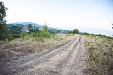 Dağ doğa yürüyüşü. Bir kadın bir sırt çantası ile dolaşıyor. Kız için üst tırmandı. Esmer dağ yolunda yürüyor. Balık gözü lens.