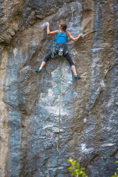 一个女人爬上岩石 一个苗条的女孩克服了艰难的攀登路线 登山者在自然的救济下训练 健身的性质 极端的爱好 美丽的岩石 露天活动 — 图库照片