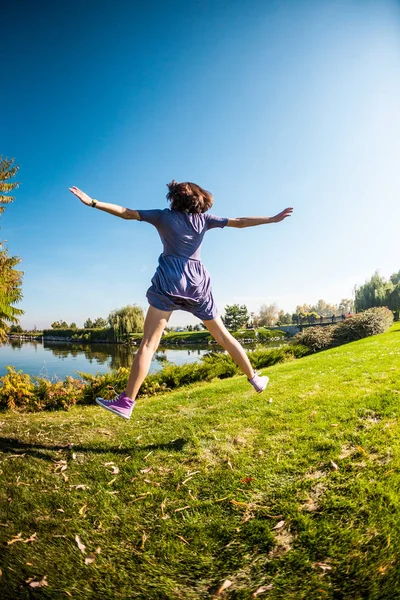 穿裙子的女孩穿过绿色的草地 在公园里散步的女人 性质的活动 苗条的黑发是乐趣 女孩跳在草地上 — 图库照片