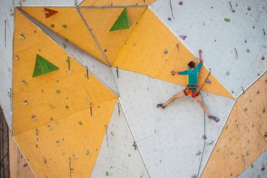Yapay bir rahatlama dağcı trenlerde. Bir kadın bir tırmanma yol sokak tırmanma duvarı üzerinde tırmanıyor. Eğitim salonunda. Güçlü kız spor dahil.