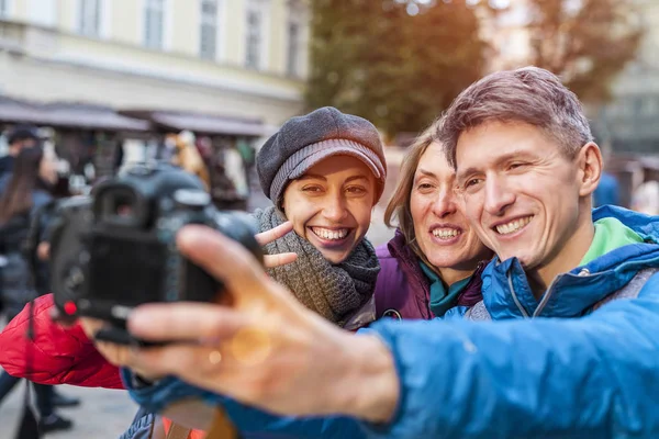 Friends take a selfie. Three friends are walking through the beautiful old town. Travel to European cities. Two women and a man are photographed against the backdrop of old buildings.