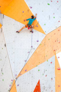 Yapay bir rahatlama dağcı trenlerde. Bir kadın bir tırmanma yol sokak tırmanma duvarı üzerinde tırmanıyor. Eğitim salonunda. Güçlü kız spor dahil.