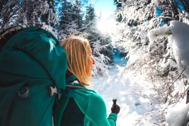 Sırt çantası kış dağlarda olan kadın. Doğal yerlere seyahat. Trekking sopa bir sarışınla portresi. Bir turist karlı bir orman yoluyla yürür. Etkin boş ve yaşam tarzı. Gülümseyen kız.