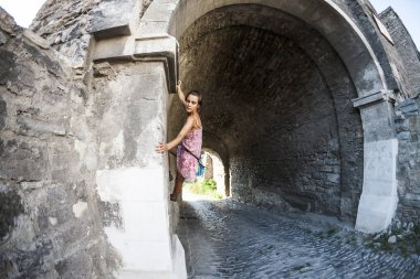 Bir kadın elbiseli bir tuğla duvara tırmanıyor. Kız taş bir çite tırmanıyor. Tırmanıcı bir şehir sokak üzerinde. Eski yıkılan binanın duvarına. Balık gözü lens.