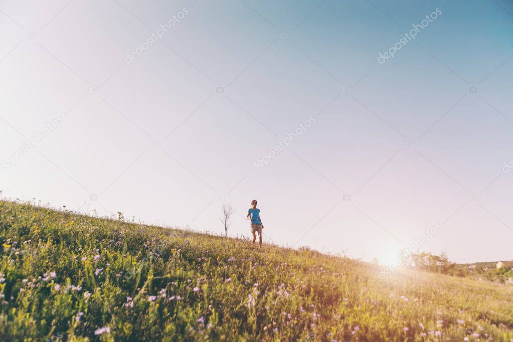 A woman is walking around the field at sunset.