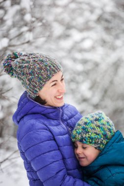 Çocuk Anne sarılmak. Bir çocuk annesi bir kış yürüyüş ile. Örme şapka içinde bir çocuk annesi ile iyi eğlenceler. Kadın oğlunu Karda oynuyor. Aile birlikte vakit geçiriyor. Aile değerleri.