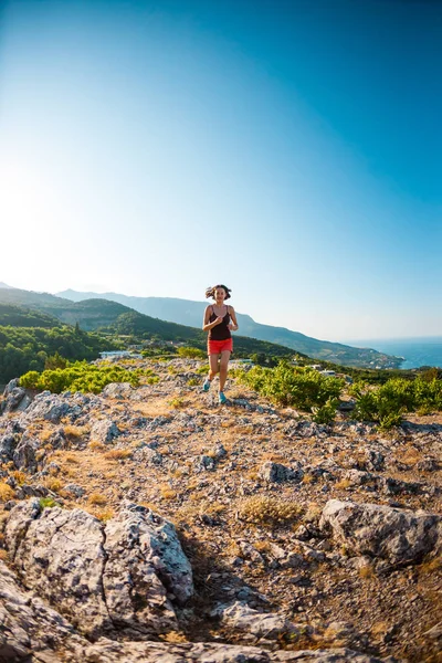 A girl is running in the mountains. A woman goes in for sports in nature. Slender brunette on top of a mountain. Skyrunning.