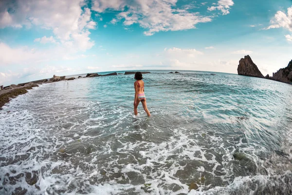 少女は 海の水に入ります 海で女風呂 海岸の残りの部分します ビーチには水着姿で細身のブルネット — ストック写真