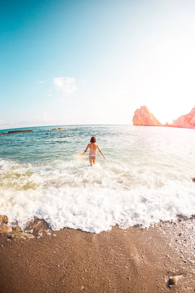 여자는 물으로 들어갑니다 여자는 바다에서 해변에는 수영복에 날씬한 — 스톡 사진
