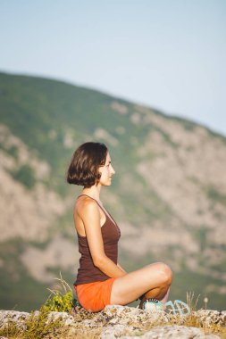 Bir kız günbatımında bir dağın tepesinde oturuyor. Bir kadın yoga devreye girer. Meditasyon medeniyet çok uzak olduğunu. Güzel doğa ve tefekkür. Dağları nın görünümü. Güzel gün batımı ışık.