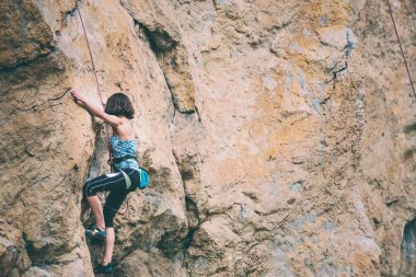 Bir kadın rock tırmanıyor. Bir ince kız zor bir tırmanış rota üstesinden gelir. Doğal bir rahatlama dağcı trenlerde. Fitness doğada. Aşırı hobi. Güzel taşlar. Açık hava etkinliği.