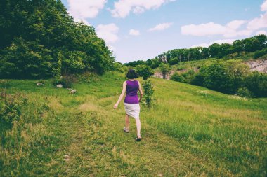 Kız bir buket çiçegi araziyi çalışır. Kadın çayırda çiçekler toplar. İnce bir esmer yeşil çimenlerin üzerinde bir güneşli bahar gününde yürür..