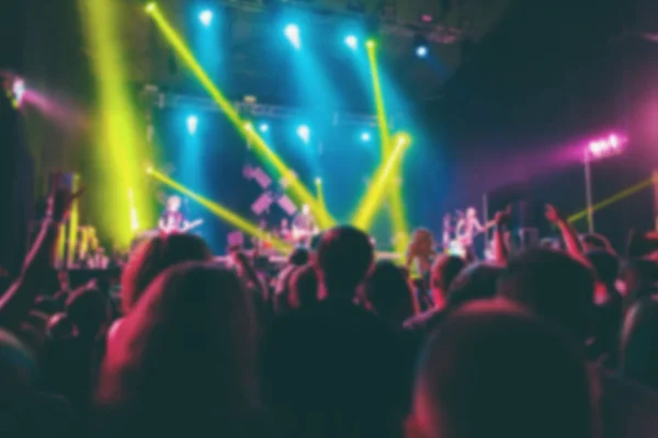 A crowd of people at the music festival. People having fun at the concert. The audience near the stage. The blur effect.