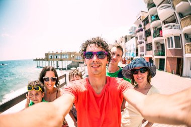 Arkadaşlar denizde sakin ol. İki aile çocukları ile seyahat. Selfies okyanus kıyısında. Kadın ve erkek tatil beldesi iskele yürümek.