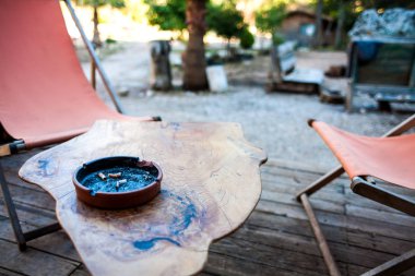 Ahşap bir masa üzerinde kül tablası. Kül tablası ile sigara izmaritleri. Bahçedeki sehpa.