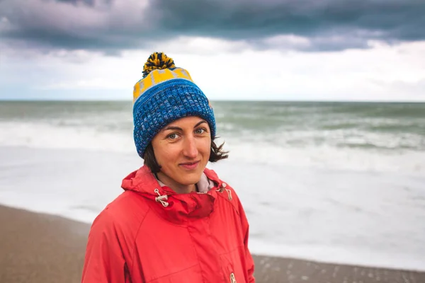 一个女人看着冬天的大海的肖像 在阴天 戴帽子的女孩沿着海边散步 秋日的波浪和天空 — 图库照片