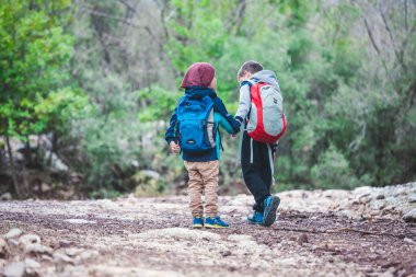 Sırt çantaları ile iki erkek bir orman yolu yürüyor. Çocuklar Parkta yürümek. Arkadaş birlikte seyahat. Çocuklar dünyayı keşfedin.