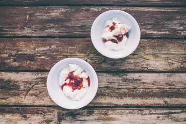 Dondurmalı çilek reçeli. İki kase yoğurt ahşap bir masa üzerinde. Kremalı dondurma berry şurubu en iyi Manzaralı.