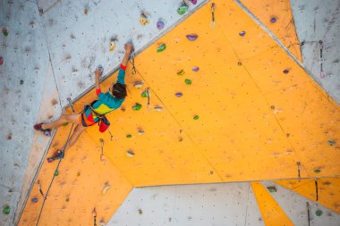 Eğitim spor tırmanma City. Güçlü bir kadın yapay arazi üzerinde tırmanma bir rota tırmanıyor. İnce kız spor dahil.