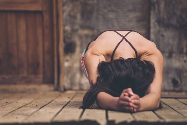 Bahçedeki yoga yaparken kadın. İnce bir esmer eski bir ev ahşap zemin üzerinde yatıyor. Kız asana yapıyor. Güzel erkek geri.