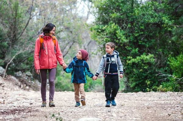 Una mujer con dos hijos atraviesa el bosque . — Foto de Stock