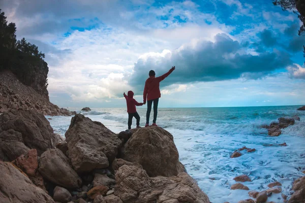 Silueta de una mujer y un niño contra el mar y el cielo . — Foto de Stock
