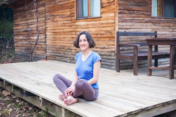 Жінка сидить на ганку старого дерев'яного будинку . — стокове фото