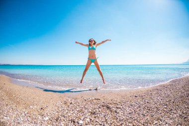 Kız sahilde atlama bir mayo içinde.