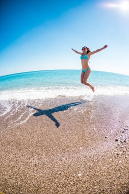 Kız sahilde atlama bir mayo içinde.