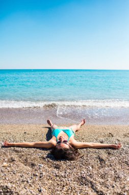 Sahilde kız sunbathes.