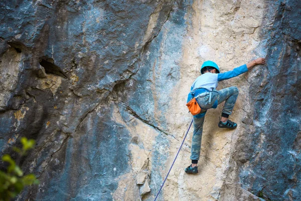 Un niño escalador trepa sobre una roca . — Foto de Stock