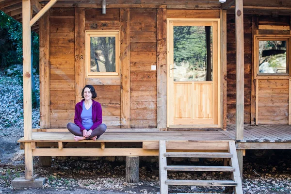 女性は古い木造住宅のポーチに座っています。. — ストック写真