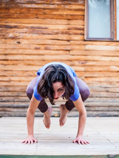 Una donna pratica yoga sotto il portico di una vecchia casa di legno . — Foto Stock