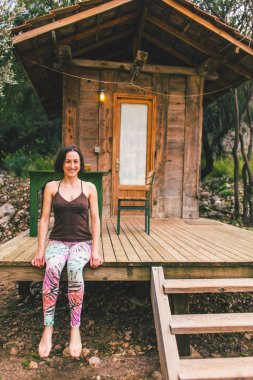 Bir kadın eski bir ahşap ev verandada oturuyor.