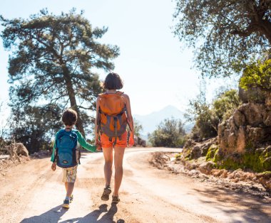 Çocuk annesi ile bir dağ yolda yürür..