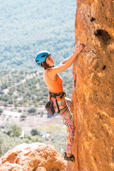 A girl in a helmet climbs a rock. — Stock Photo, Image