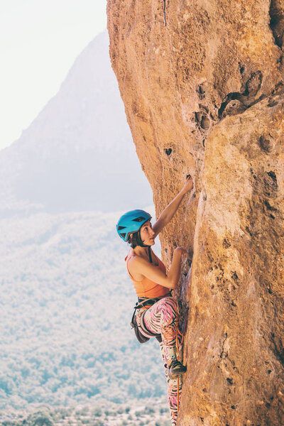 A girl in a helmet climbs a rock.