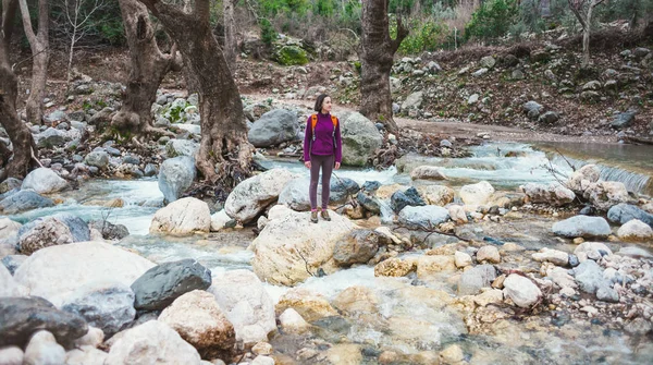 Een vrouw met een rugzak staat in de buurt van een rivier berg. — Stockfoto