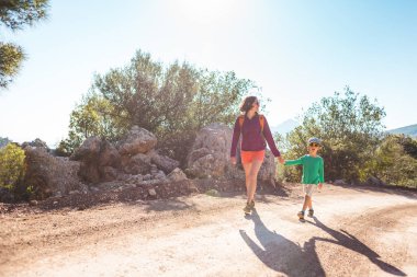 Çocuk annesi ile bir dağ yolda yürür..