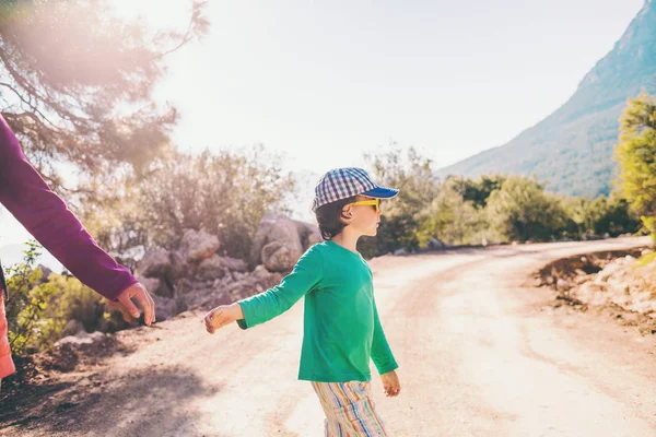 stock image The boy walks with his mother on a mountain road.