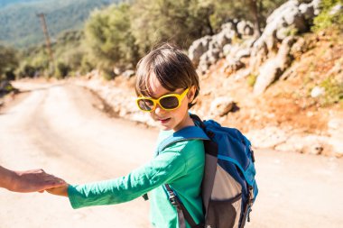 Çocuk annesi ile bir dağ yolda yürür..